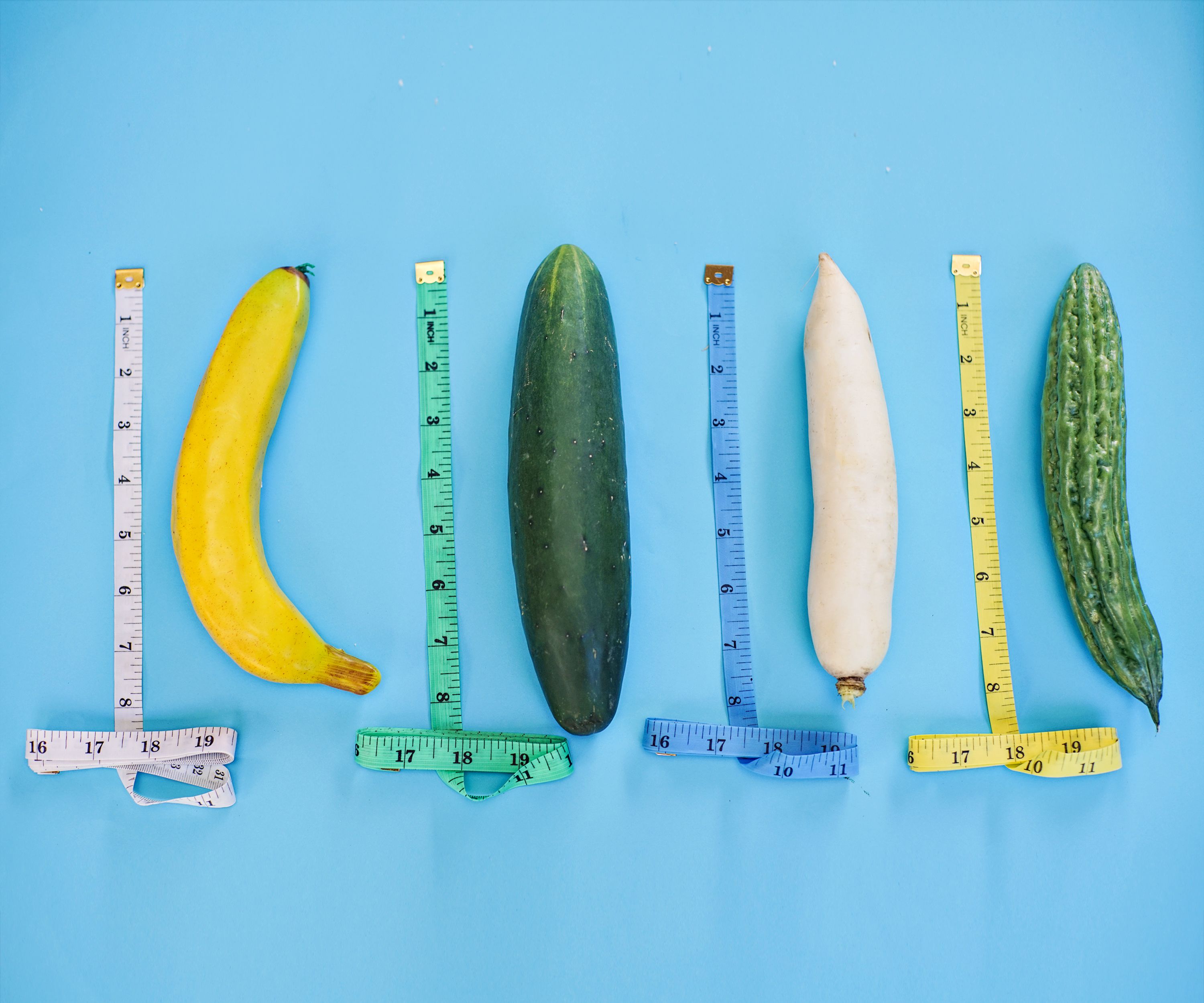 Various vegetables with measuring tapes on blue background