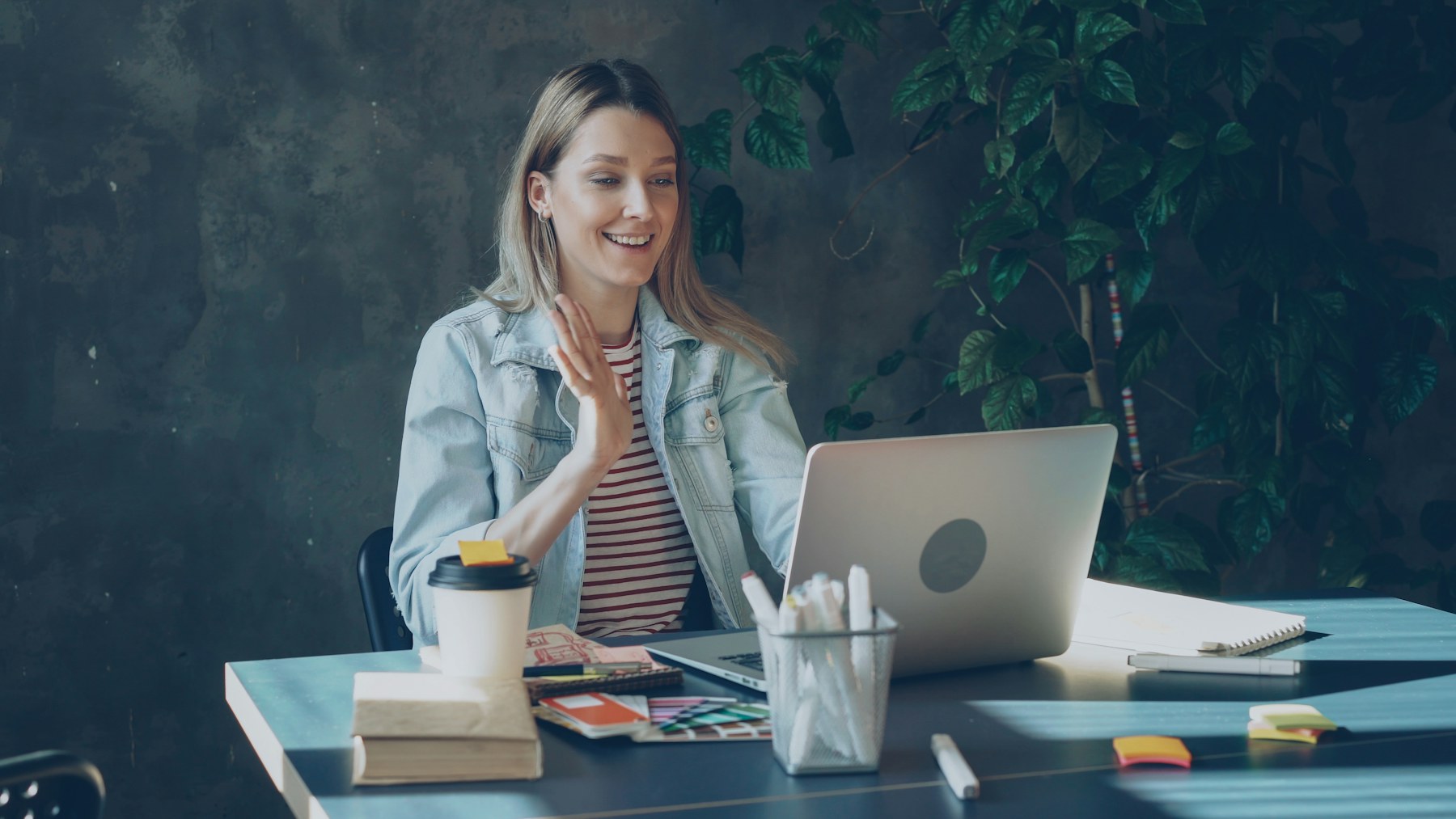 Founder smiling and waving at her laptop